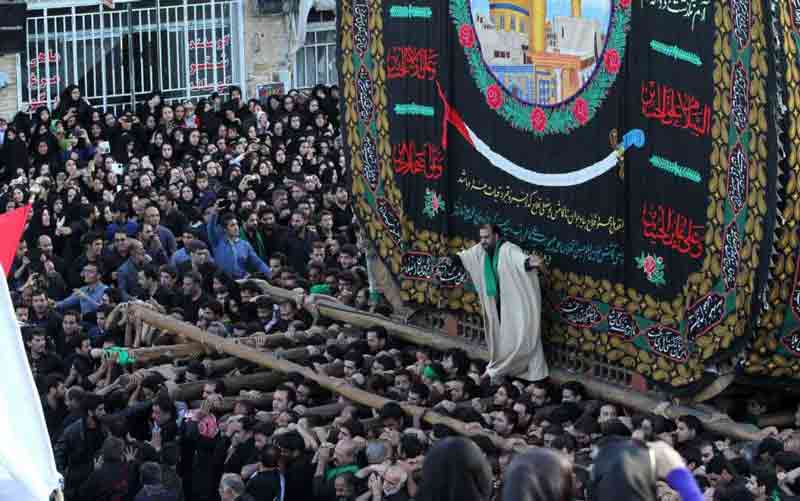 People carrying a heavy structure called Nakhl on their shoulder at the time of Ashura in Iran